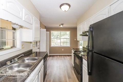 A kitchen with a black refrigerator and a sink.