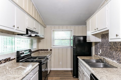 A kitchen with black appliances and white cabinets.