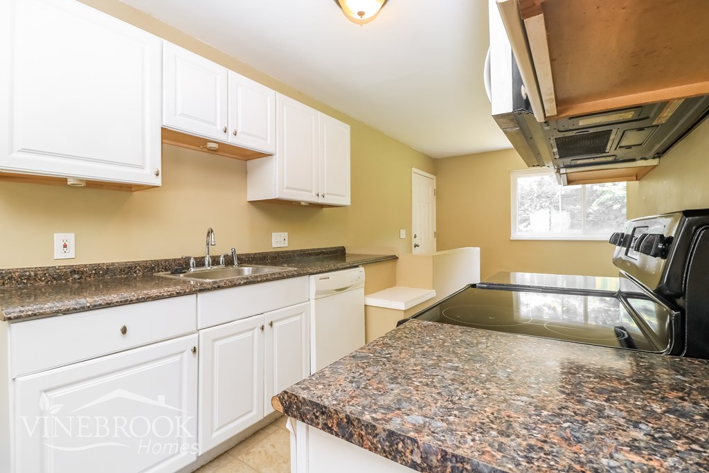 A kitchen with granite countertops and white cabinets.
