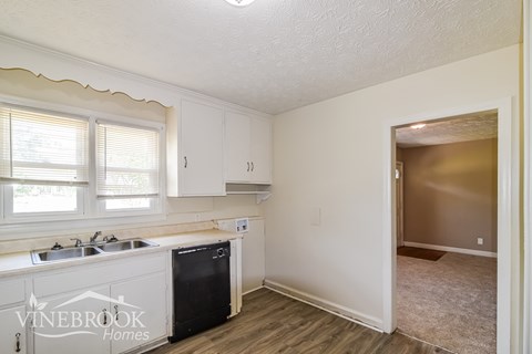 A kitchen with white cabinets and a black dishwasher.