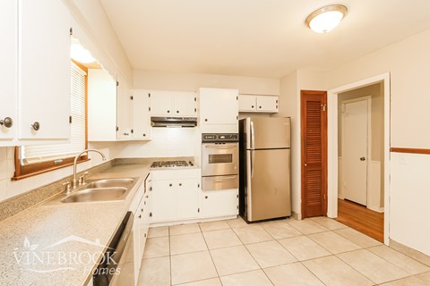 A kitchen with white cabinets and a stainless steel refrigerator.
