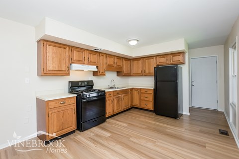 A kitchen with wooden cabinets and a black refrigerator.