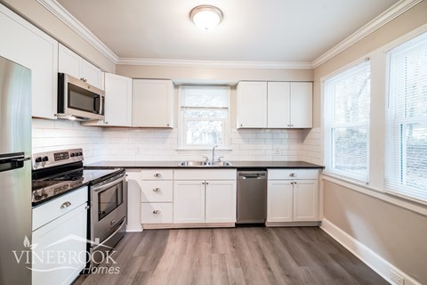 A kitchen with white cabinets and a black countertop.