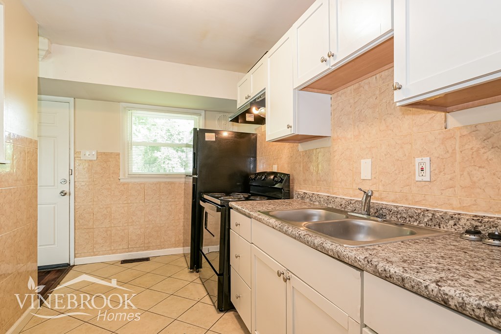 A kitchen with a black refrigerator and a sink.