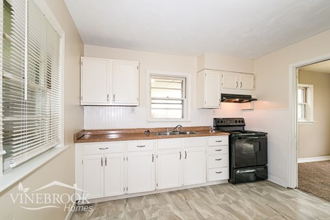 A kitchen with white cabinets and a black oven.