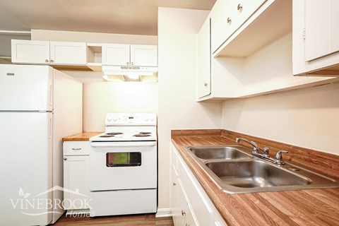 A kitchen with a white fridge, stove and cabinets.
