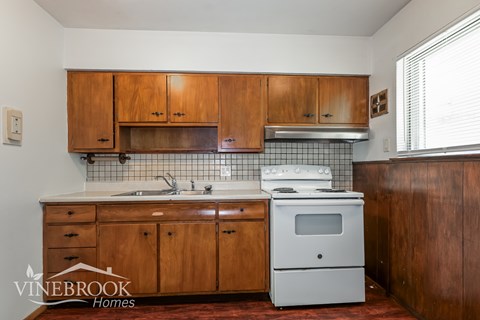 A kitchen with wooden cabinets and a white stove top oven.
