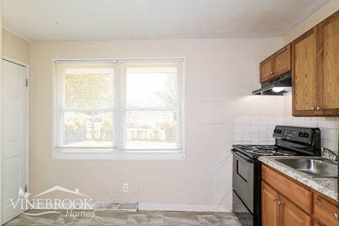 A kitchen with a stove, sink, and cabinets.