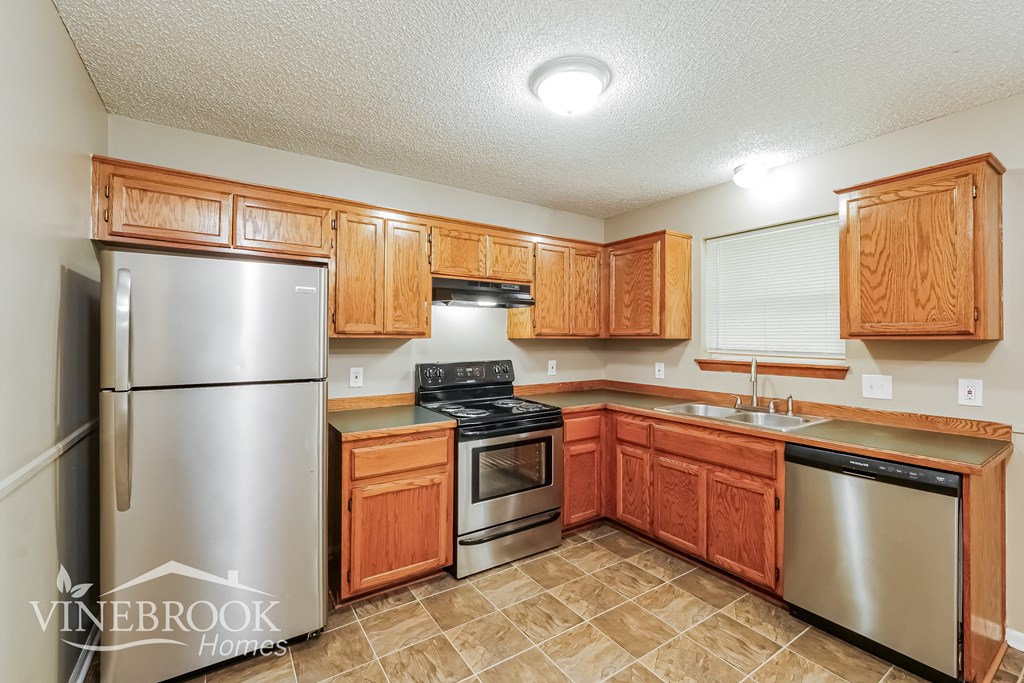 A kitchen with wooden cabinets and a stainless steel refrigerator.