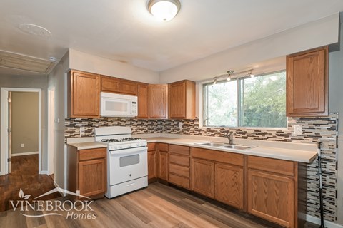 A kitchen with wooden cabinets and a Vinebrook Homes logo.