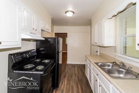 A kitchen with a black stove top oven and white cabinets.