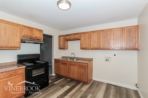 A kitchen with wooden cabinets and a black stove top oven.
