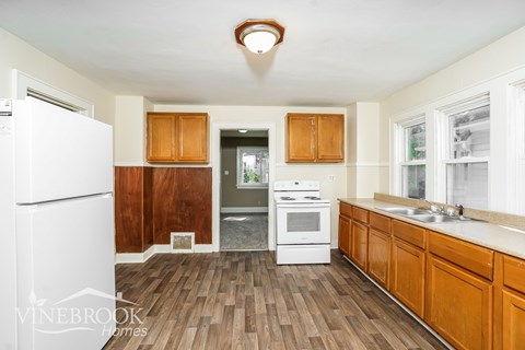 A kitchen with wooden floors and white appliances.