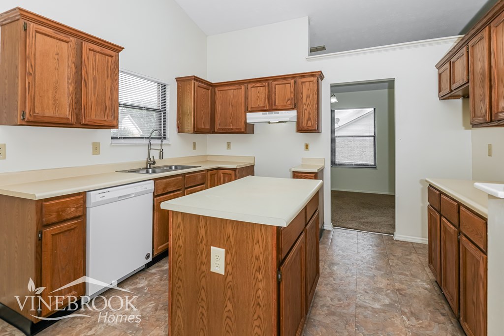 A kitchen with wooden cabinets and a white dishwasher.