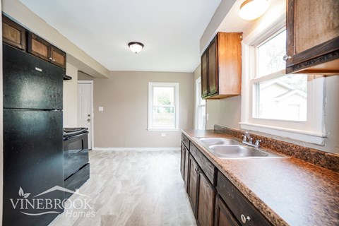 A kitchen with a black fridge and wooden cabinets.