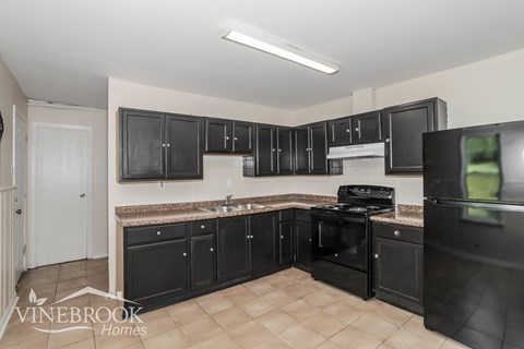 A kitchen with black cabinets and appliances is shown.