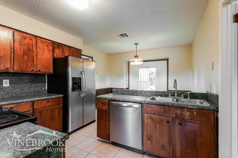 A kitchen with wooden cabinets and a stainless steel refrigerator.