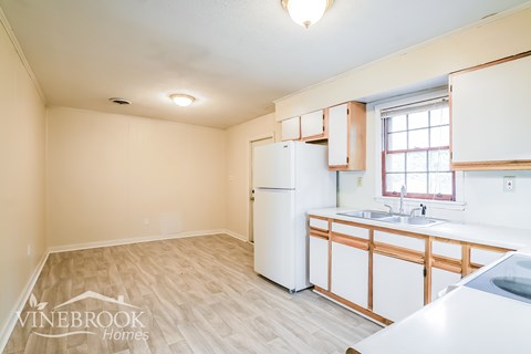 A kitchen with a white refrigerator and wooden cabinets.