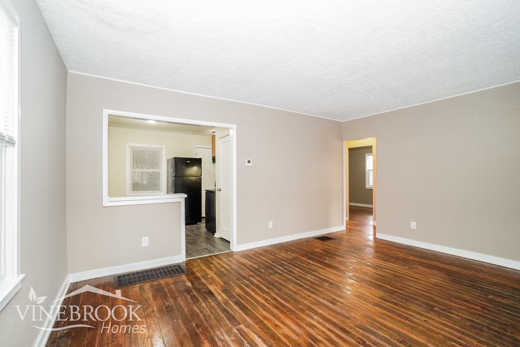 the living room and dining room of an empty house with wood flooring