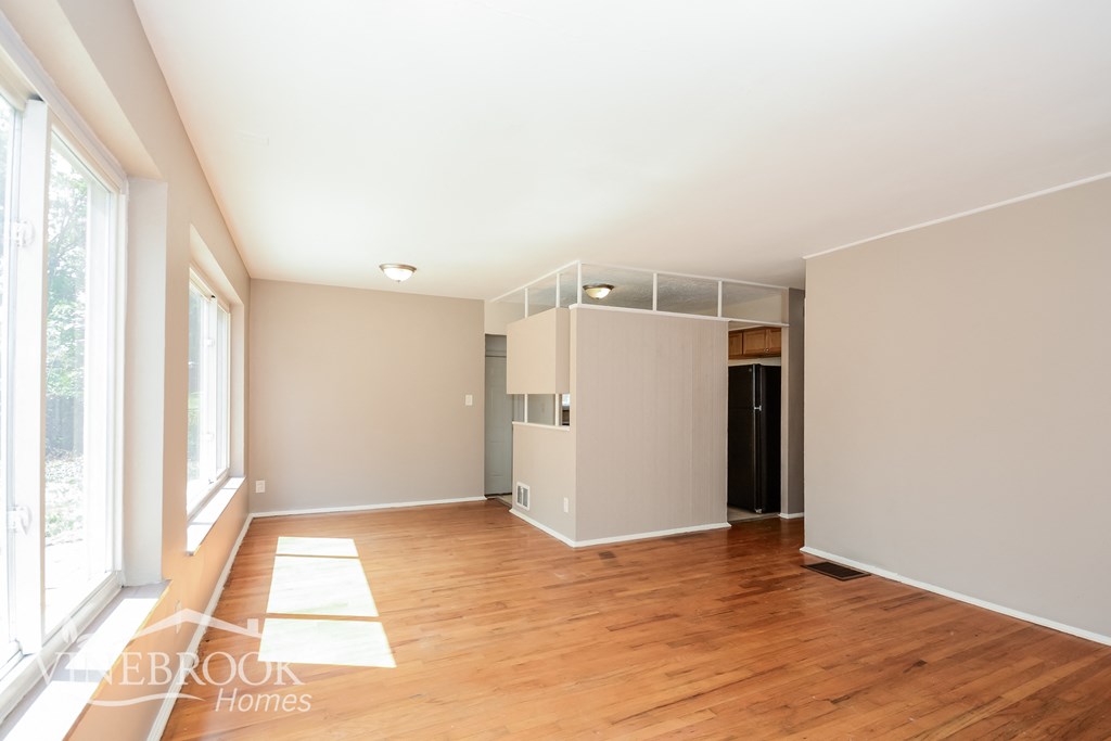 an empty living room with wood flooring and white walls