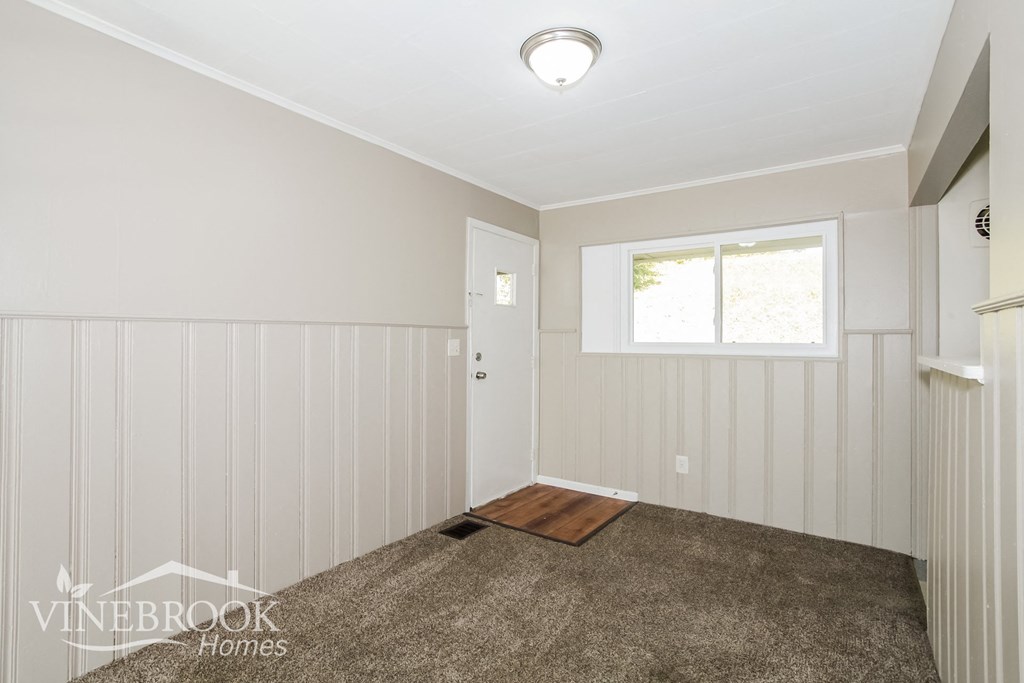 a small carpeted room with a door and a window