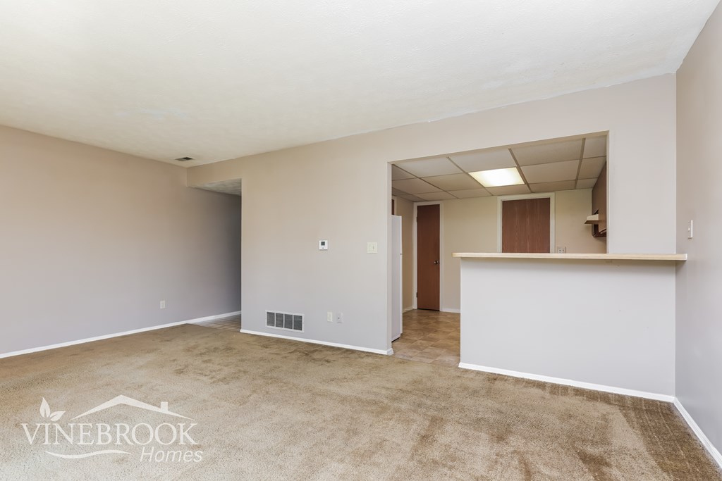 A spacious room with a carpeted floor and a reception desk.