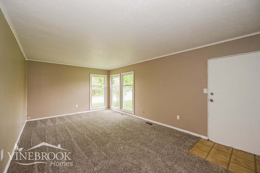 A room with a carpeted floor and a door leading to a balcony.