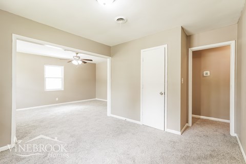 A spacious room with a carpeted floor and a ceiling fan.
