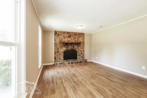 A living room with a fireplace and wooden floors.