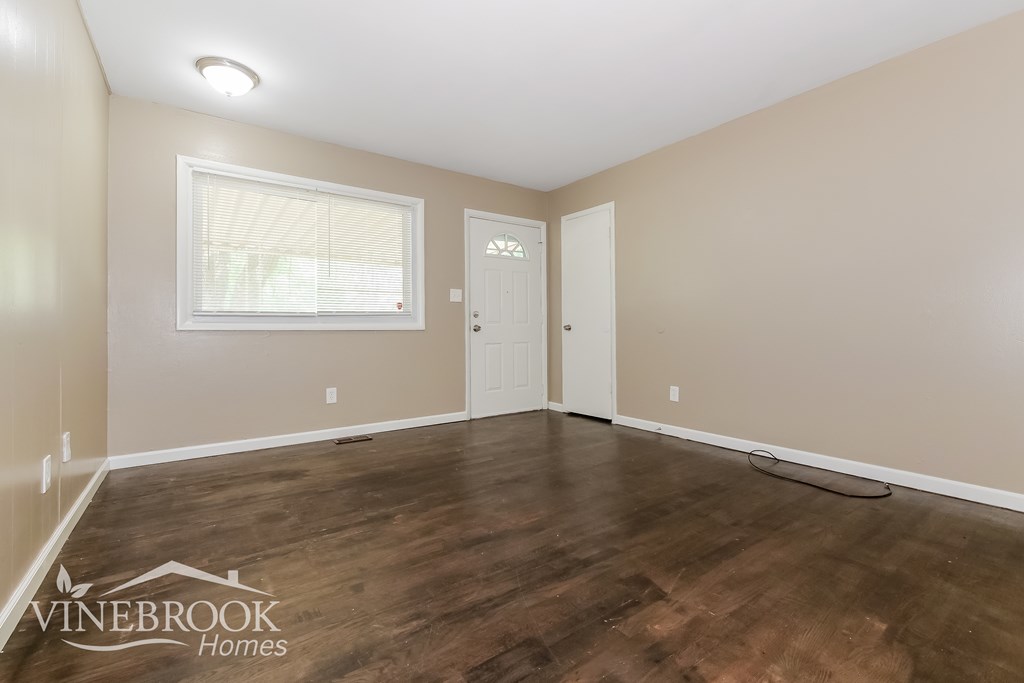 A room with a window and two doors, one of which is open, with a Vinebrook Homes logo on the bottom left.