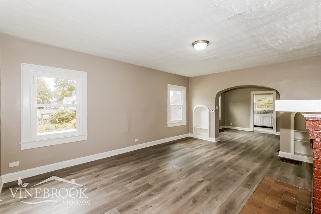 A spacious room with wooden flooring and a large window.