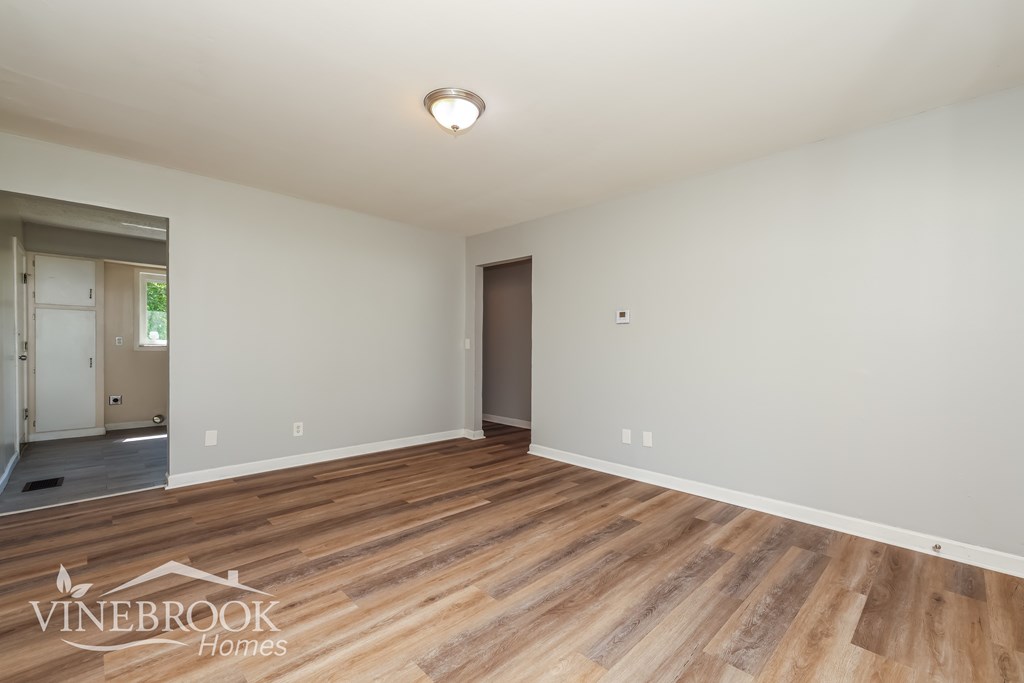 A room with wooden flooring and a door on the right side.
