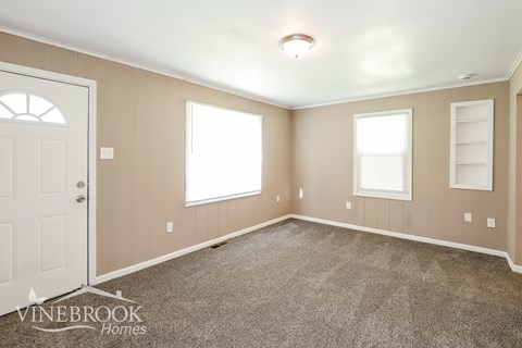 A room with a carpeted floor and a door on the left.