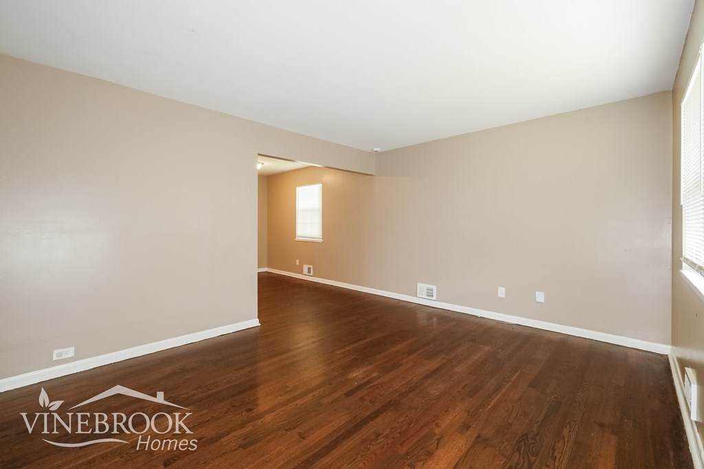 A room with wooden floors and a window on the right side.