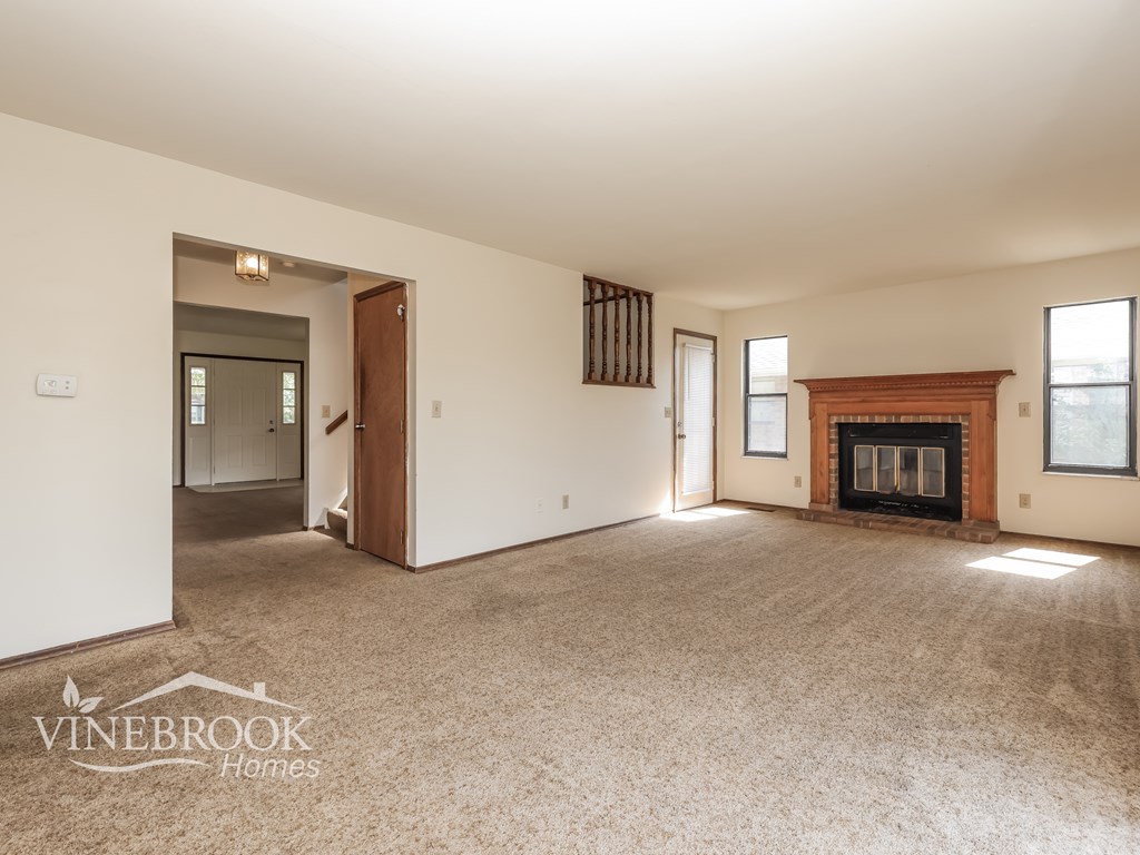 A spacious room with a fireplace and a carpeted floor.