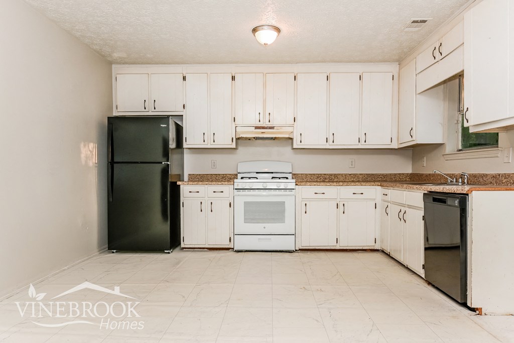 a white kitchen with white cabinets and black appliances