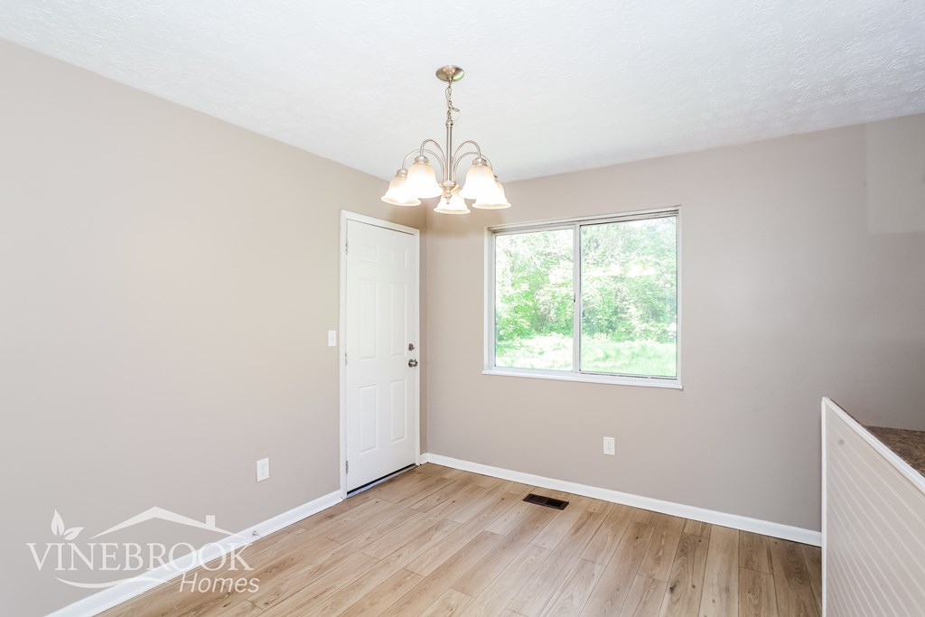 A room with a door and a window with a chandelier hanging from the ceiling.