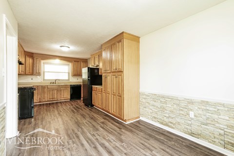A kitchen with wooden cabinets and a stone wall.