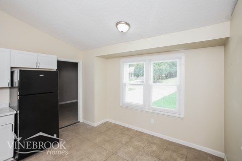 a kitchen with a black refrigerator and a window