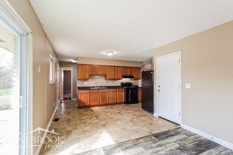 A kitchen with wooden cabinets and a black fridge is shown.