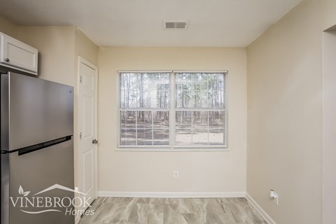 A kitchen with a refrigerator and a window with blinds.