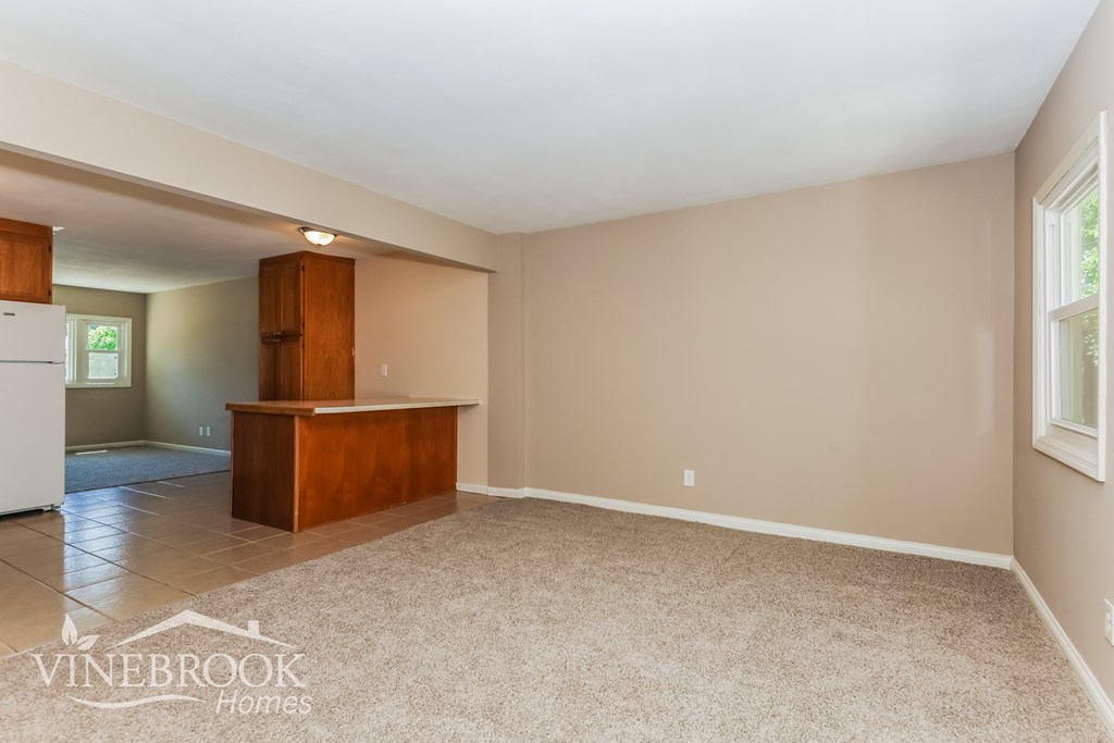 an empty living room with a dining room table and a kitchen
