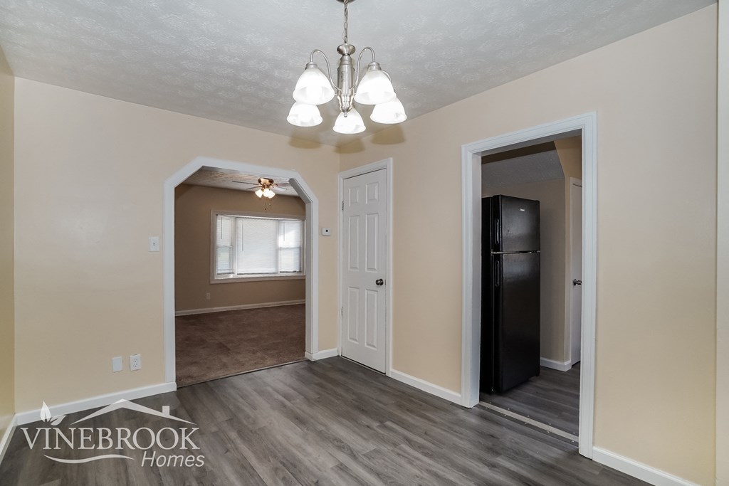 the kitchen and dining room of a home with white walls and wood flooring
