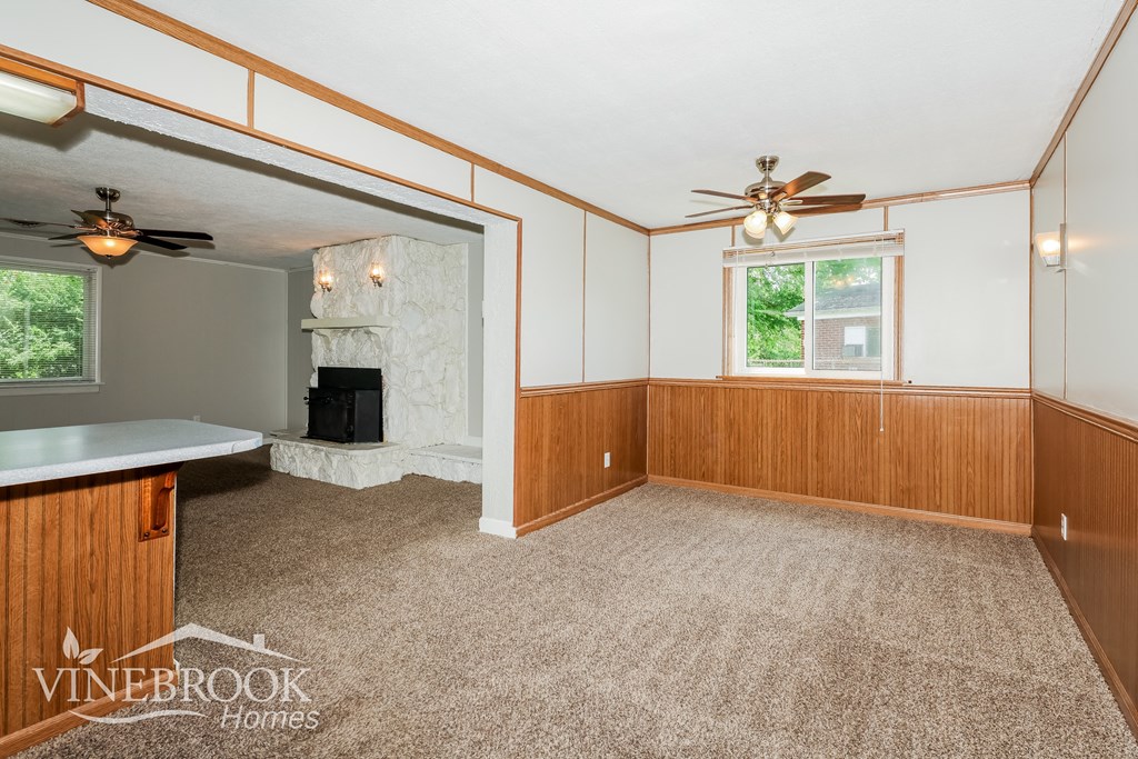 a kitchen and living room with wood paneling and a fireplace