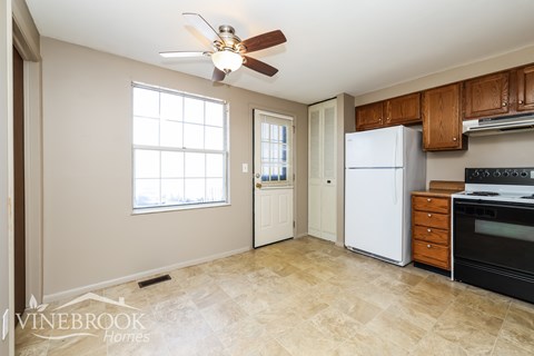 A kitchen with a fan, refrigerator, and oven.