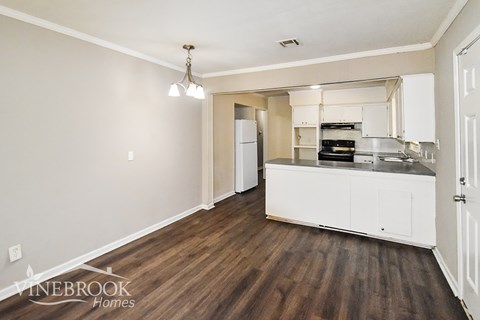 A kitchen with white cabinets and a wooden floor.