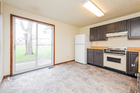 A kitchen with a white refrigerator and black cabinets.