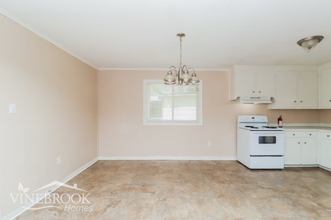 A kitchen with a white stove and cabinets.