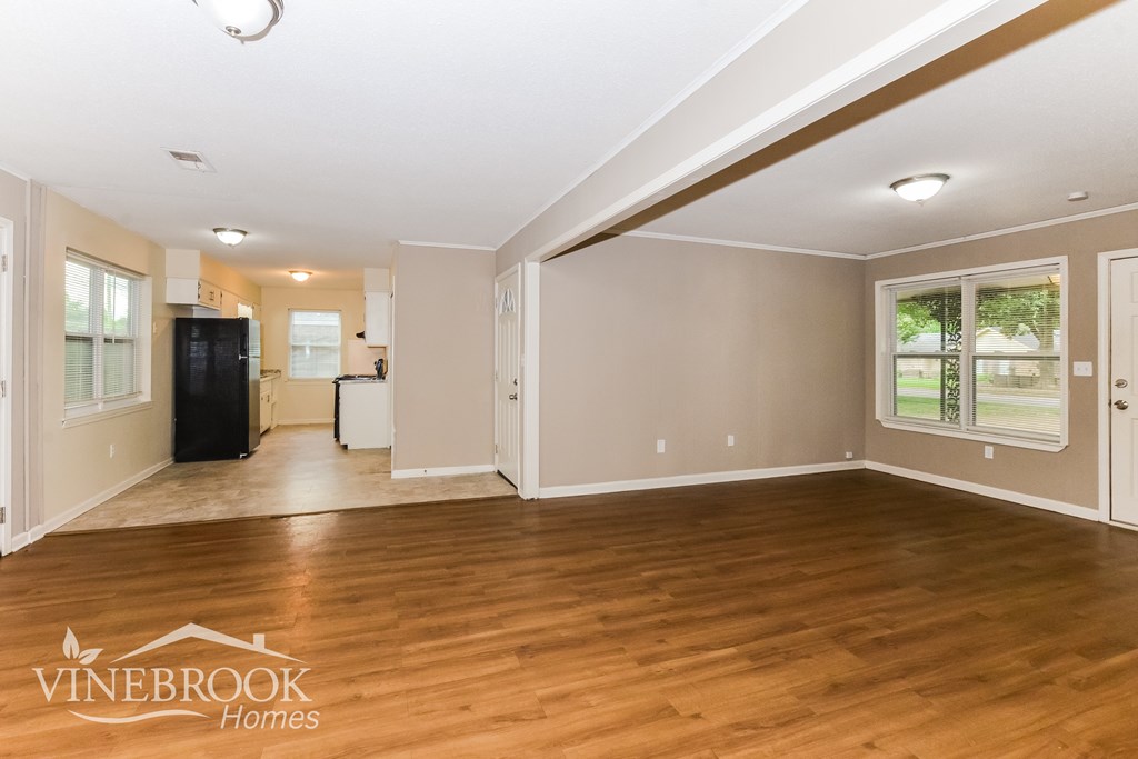 A spacious room with wooden floors and a Vinebrook Homes logo.