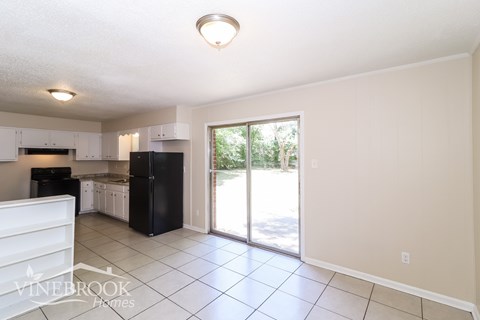 A kitchen with white cabinets and black appliances with a window.